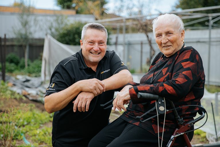 Man smiling next to elderly woman in garden