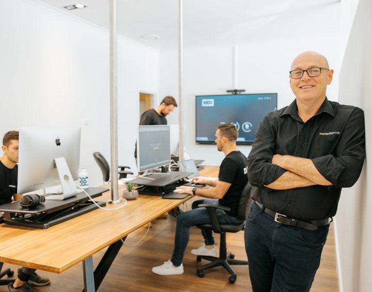Team working on computers in a modern office with a manager standing