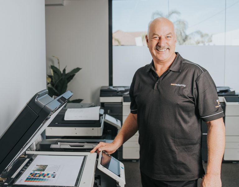 Smiling man operating a copier in an office