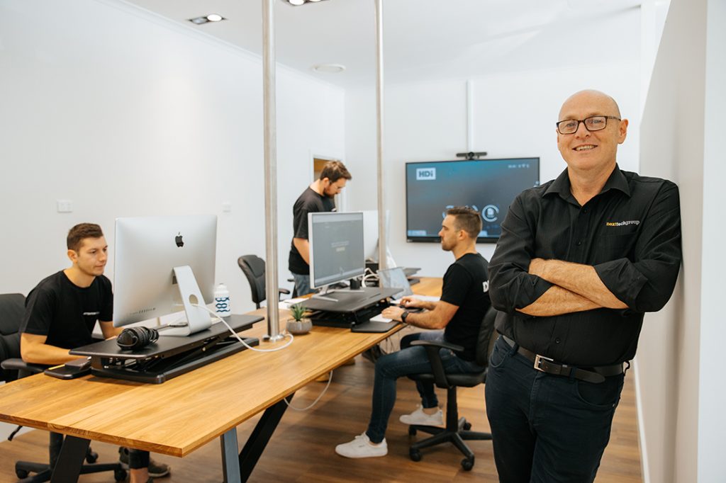 Team working on computers in a modern office with a manager standing