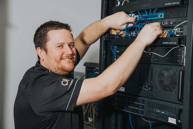 Smiling IT technician working on server rack