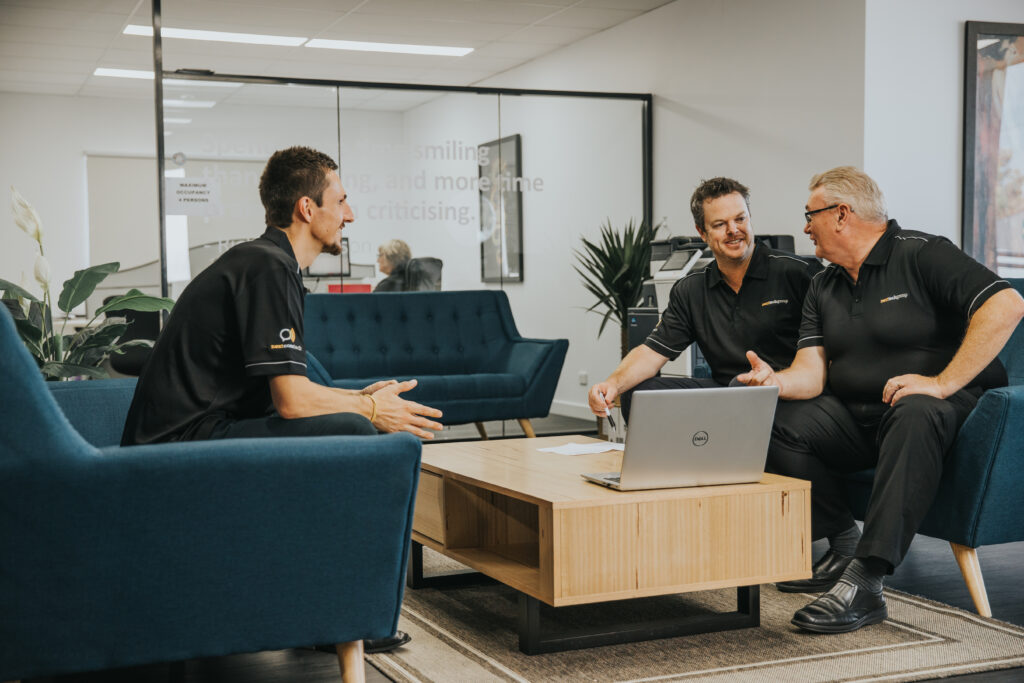 3 men sat on sofas in an office discussing work