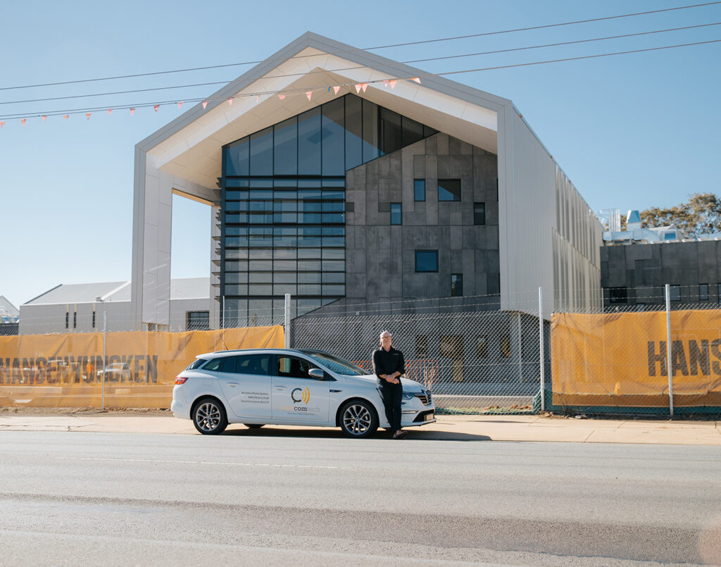 man standing in front of a next tech group car with building in background