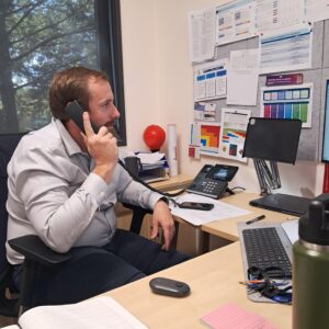 man at school desk on the phone using 3cx technology