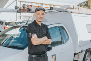 man in next tech uniform smiling in front of a van