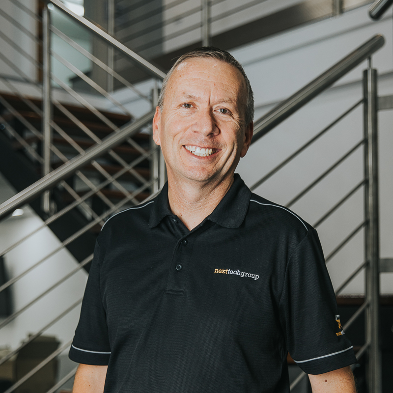 man in next tech group uniform smiling at camera