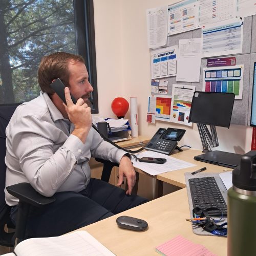 man at school desk on the phone using 3cx technology