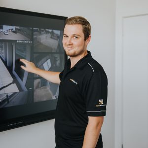 man in front of interactive screen showing security software smiling at camera