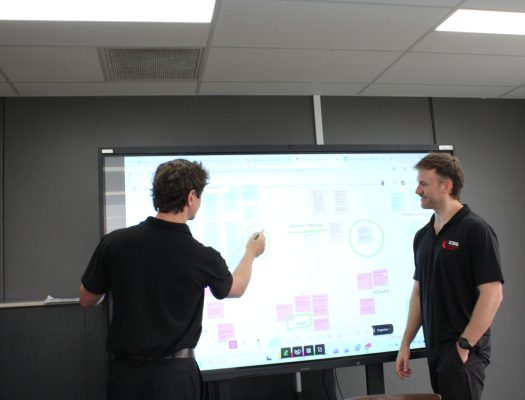 2 men in a board room using an interactive touch screen