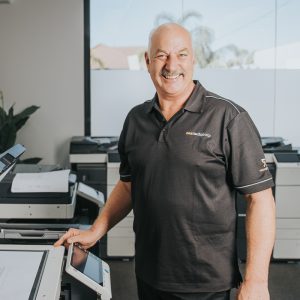 Man in Next Tech Group uniform standing by the printer